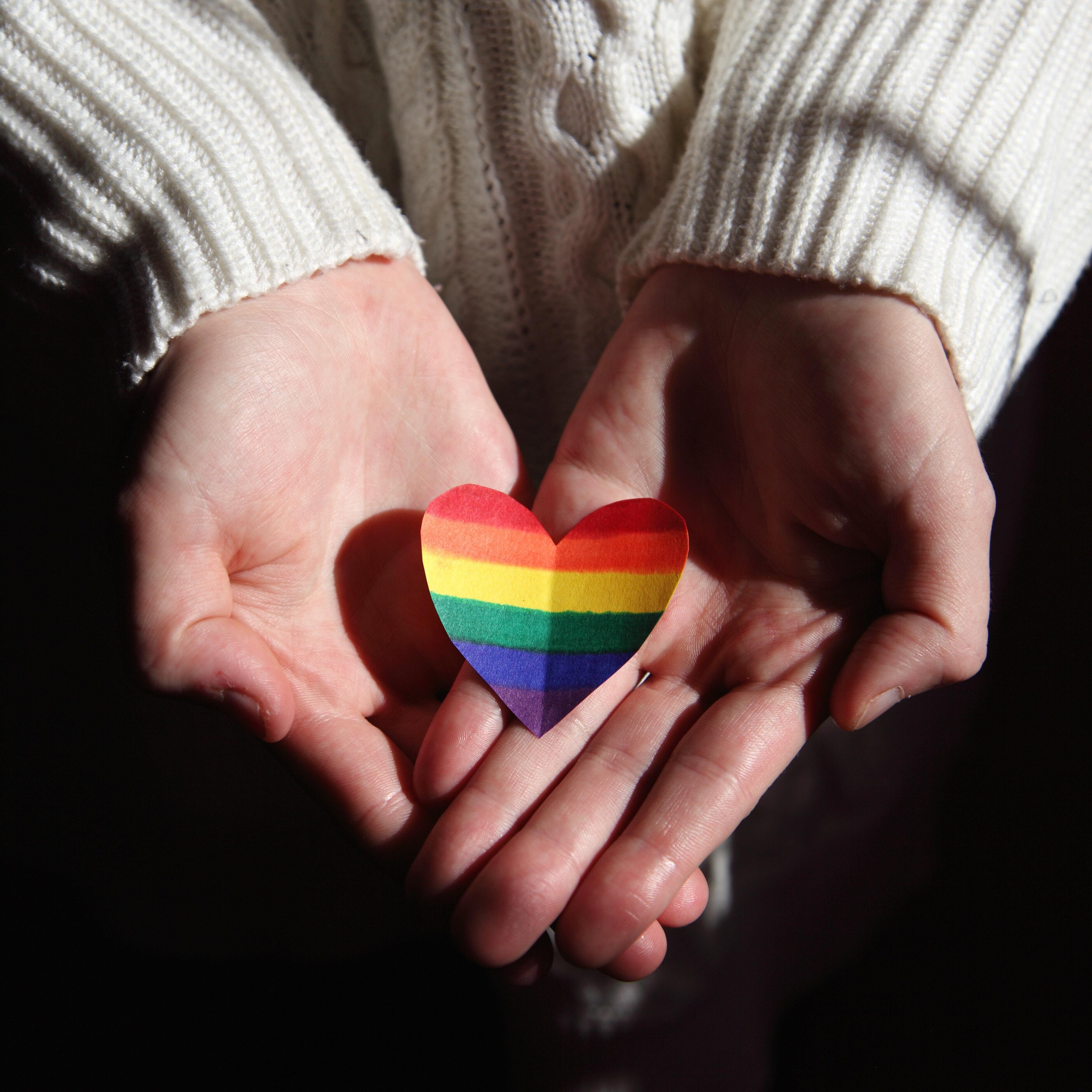 Hands holding a rainbow heart